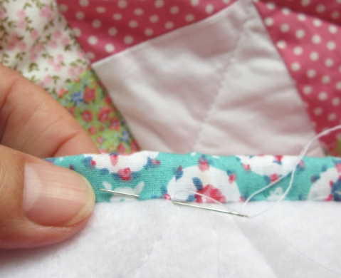 Replace the needle just under where it appears out through the binding. Check your stitch isn't visible from the right side of the patchwork.